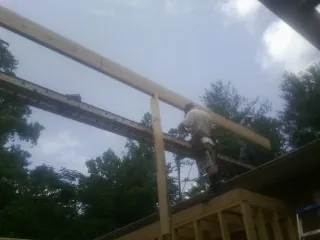 Carpenter setting a ridge beam over a new addition frame — Ice Dam Removal by Roofing Brothers in Hoskins