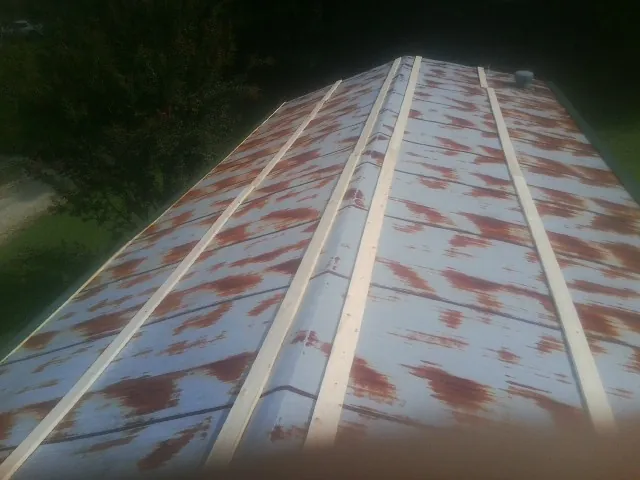 Rusted metal roof panels with new wood purlins before replacement — Storm Damage Roof Repair in Hoskins by Roofing Brothers