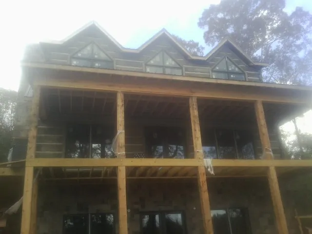 Dormers and porch framing on a large log home under construction — Roof Coating work by our crew in Hoskins