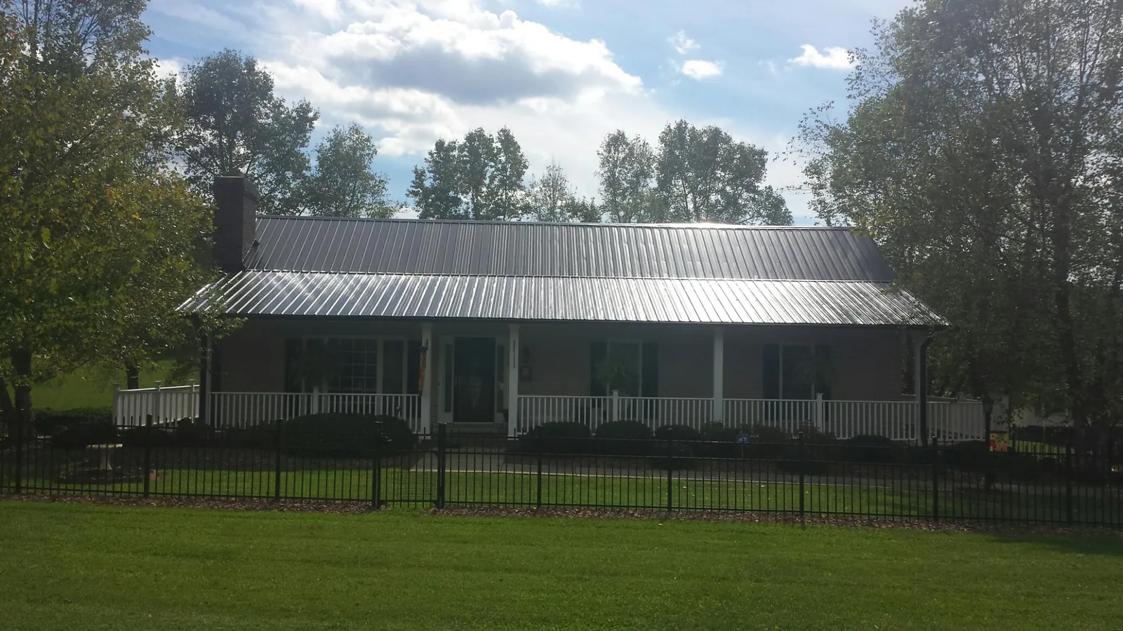 Gray metal roof on a brick ranch with a full width front porch — Gutter Guard Installation work by our crew in Hoskins