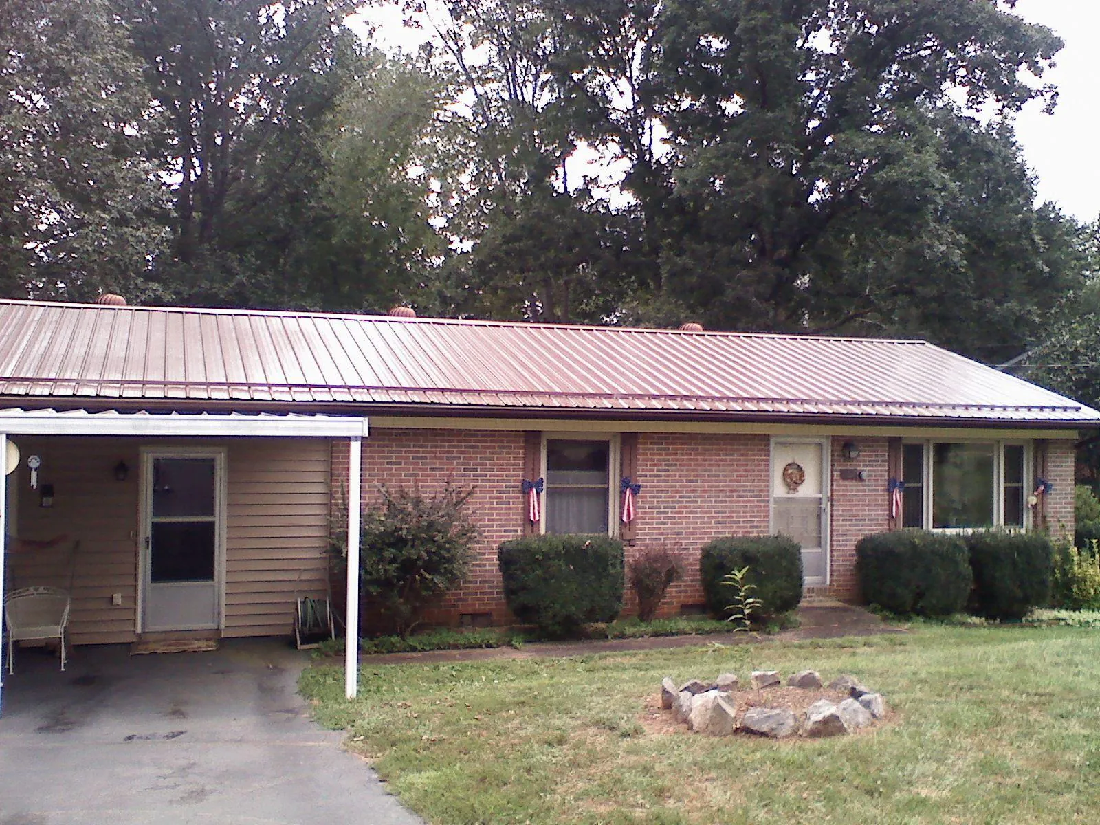 Bronze metal roof and carport on a brick ranch home — Roof Repair work by our crew in Hoskins